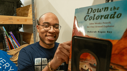 Elan volunteer selecting a book from a shelf. 