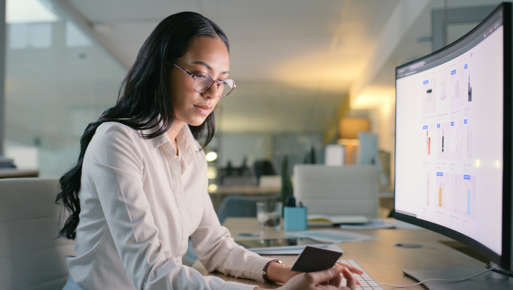 A woman sits at a desk facing a computer screen. 